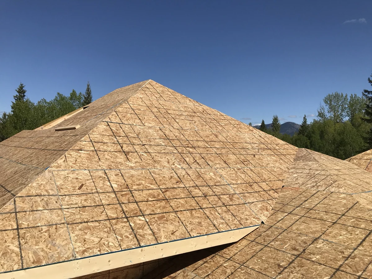 A fully sheathed hip roof with clean ridges and valleys under a clear Montana sky