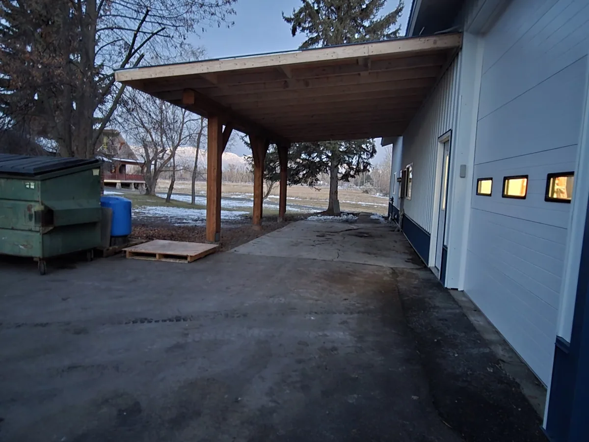 Looking down the length of a heavy timber covered walkway with exposed rafters and a finished wood soffit
